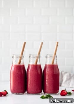 Three bottles of red berry chia smoothie with bamboo straws, ready to be enjoyed.