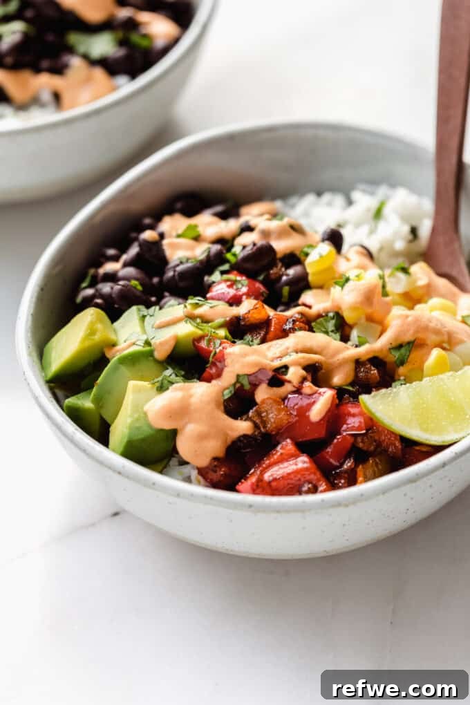 A close-up of a single vegan burrito bowl, perfectly topped with a generous drizzle of creamy chipotle crema.