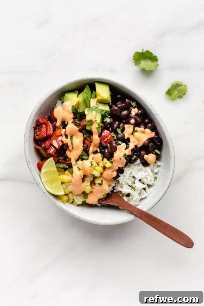 A beautifully composed vegan burrito bowl featuring a medley of black beans, corn, fresh avocado, and vibrant sautéed peppers, ready to be enjoyed.