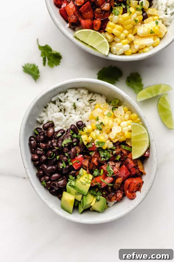Two beautifully assembled vegan burrito bowls, rich with vegetables, rice, black beans, peppers, and avocado.