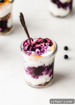 A beautifully assembled jar of yogurt with blueberry compote and mango, ready to be served and enjoyed.