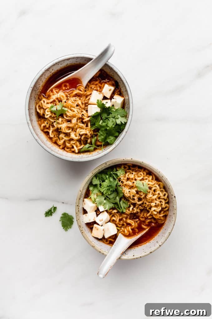 Fiery Kimchi Ramen 2 Two bowls of vibrant Kimchi Ramen, garnished with fresh cilantro, showcasing chewy noodles and soft tofu cubes.