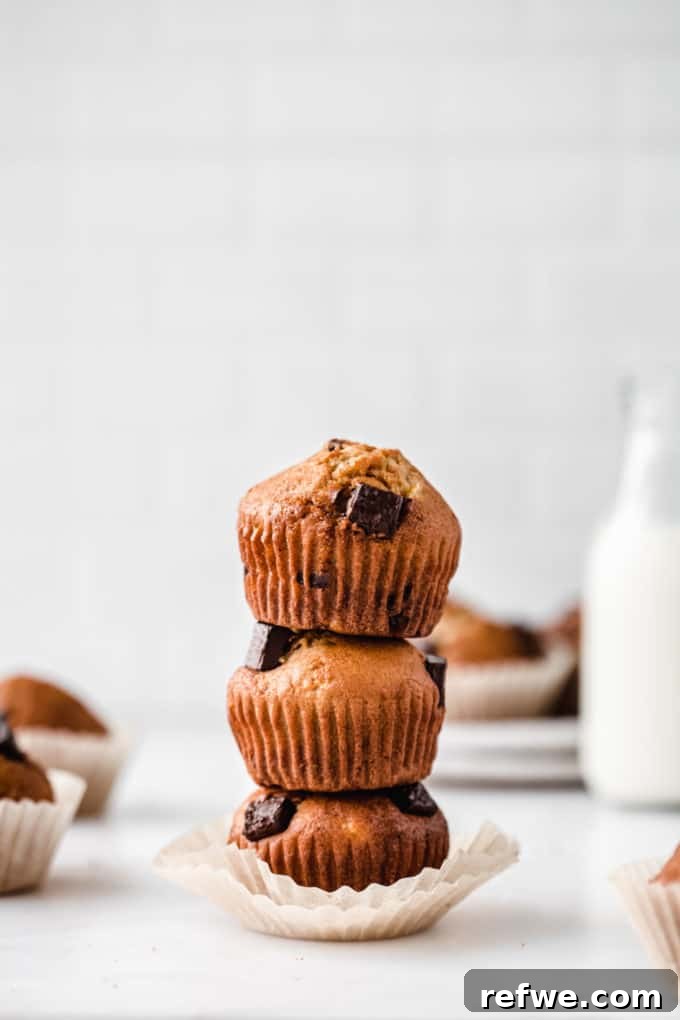 Wholesome Chocolate Chip Banana Muffins 7 Three healthy chocolate chip banana muffins stacked with a rustic jar of milk in the soft-focused background.