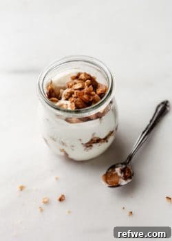 A jar of apple pie parfait with a spoon on the side, showcasing the delicious layers.