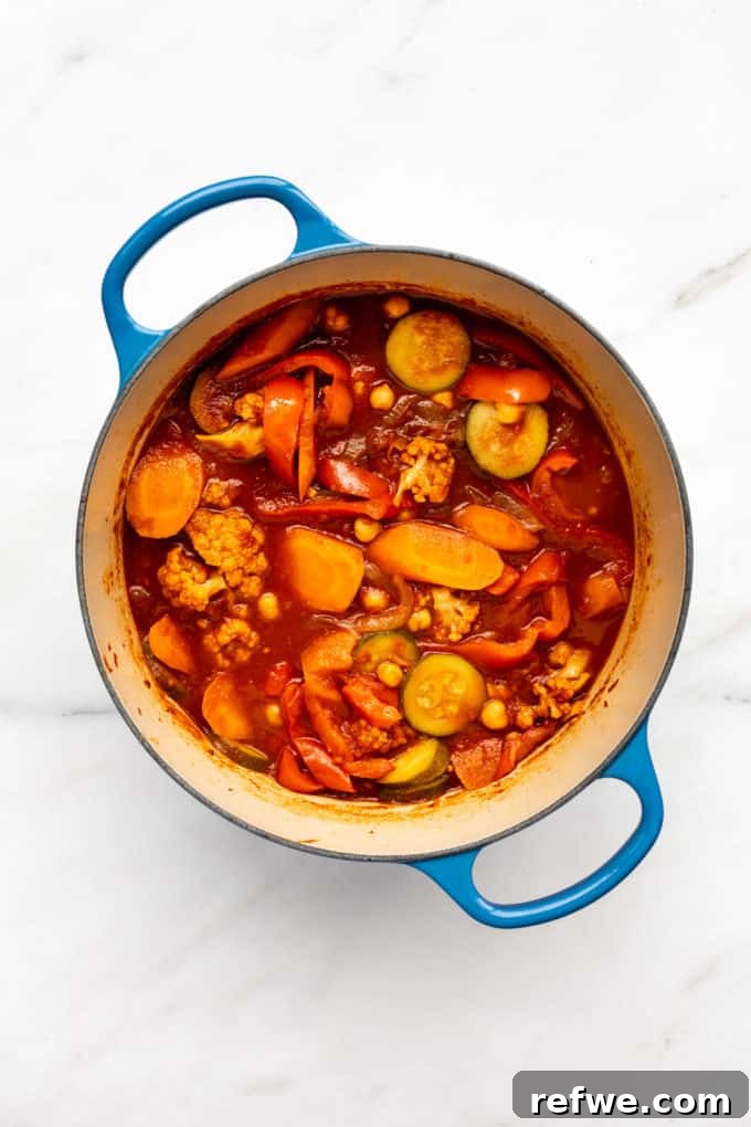 Moroccan Spice Garden Tagine 5 A blue pot filled with a vibrant Spiced Vegetable Tagine, simmering gently, with a rich, inviting sauce.