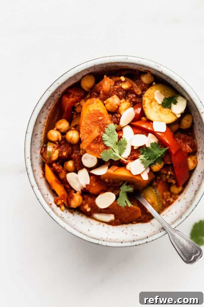 Moroccan Spice Garden Tagine 6 A beautifully presented bowl of vegetable tagine, generously topped with toasted almonds and fresh cilantro, highlighting its richness.