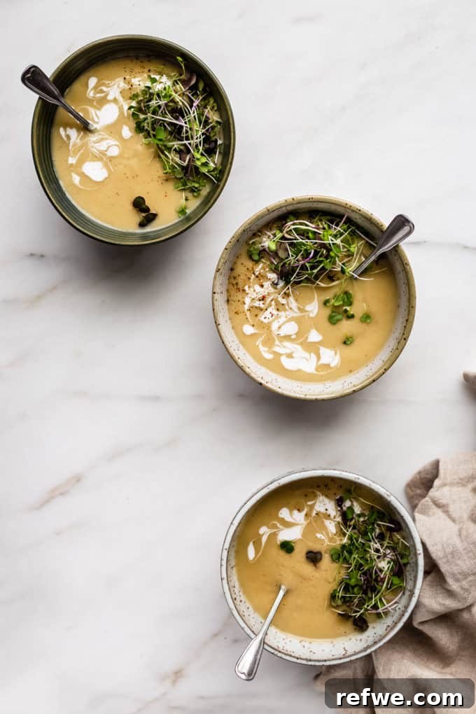 Comforting Slow-Roasted Garlic Soup 2 three bowls of roasted garlic soup on a marble board with a beige napkin on the side