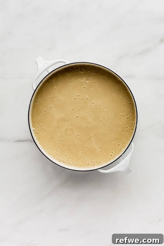 Comforting Slow-Roasted Garlic Soup 5 a pot of roasted garlic soup on a marble board