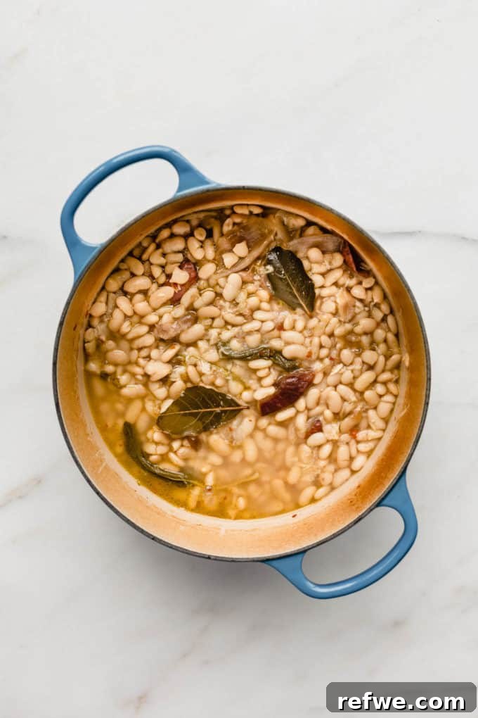 Oven Braised Beans 4 A blue pot of brothy beans, freshly baked, with the cannellini beans now tender and submerged in a rich, simmering broth, ready to be served.