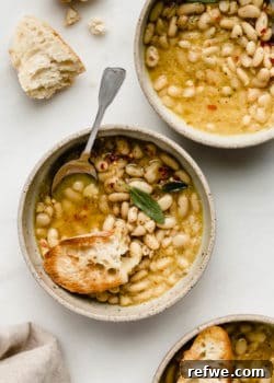 A close-up of cannellini beans in broth with crusty bread for a warm, comforting meal.