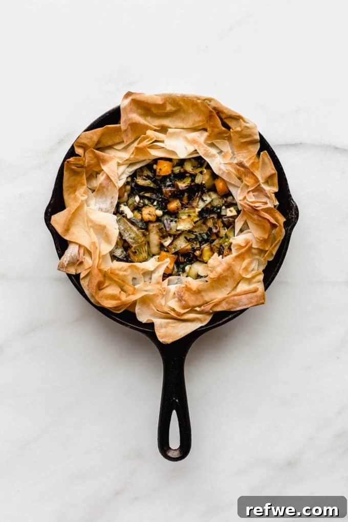 A golden brown veggie skillet phyllo pie baked to perfection in a rustic cast iron skillet, ready to be served.