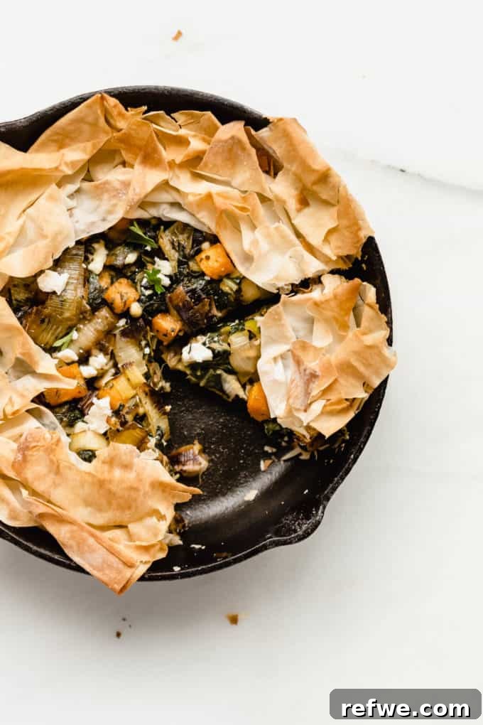 A perfectly baked veggie skillet pie in a cast iron skillet, its golden phyllo crust gleaming, ready for slicing.