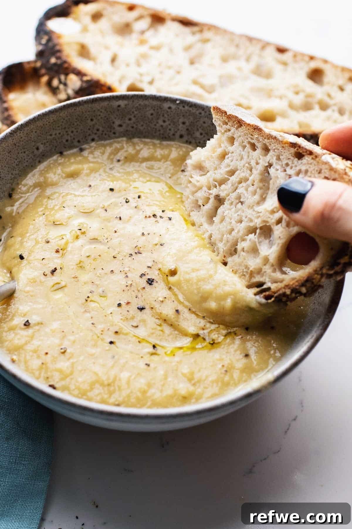 Heartwarming Plant-Based Soups for Cozy Days 17 A bowl of creamy white cauliflower soup, garnished with green herbs.