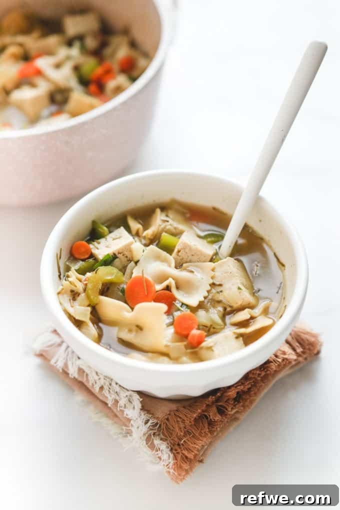 Heartwarming Plant-Based Soups for Cozy Days 24 A comforting bowl of vegan tofu chicken noodle soup with herbs.