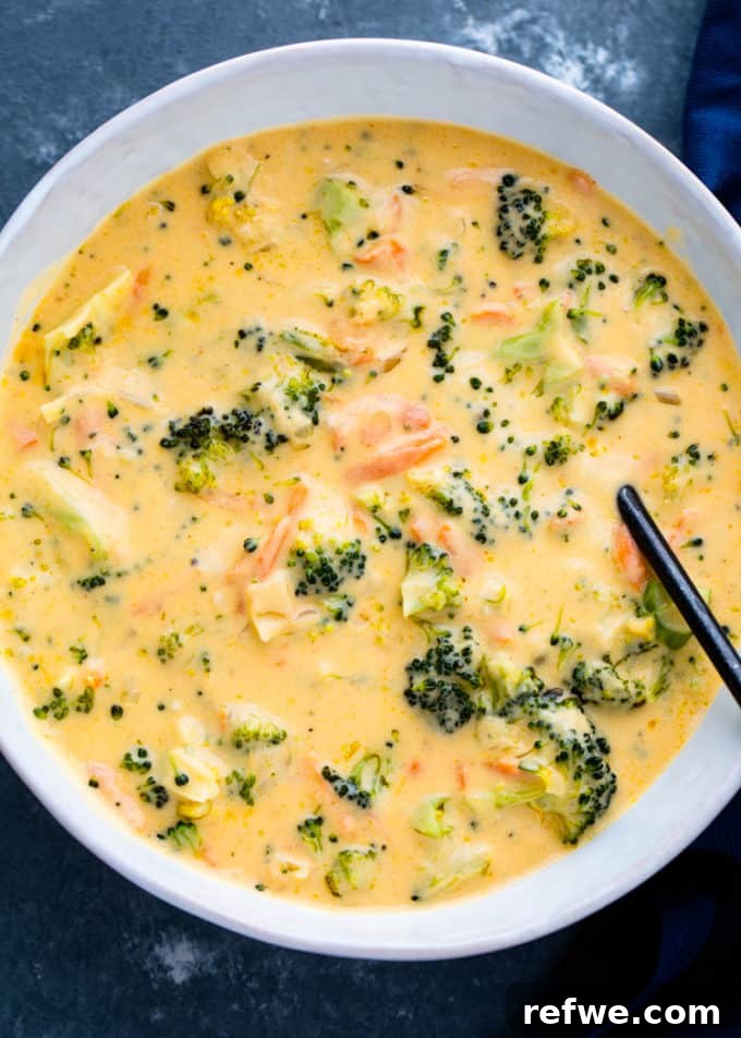 Heartwarming Plant-Based Soups for Cozy Days 26 A creamy, rich bowl of broccoli cheddar soup with visible broccoli florets and shredded cheese.