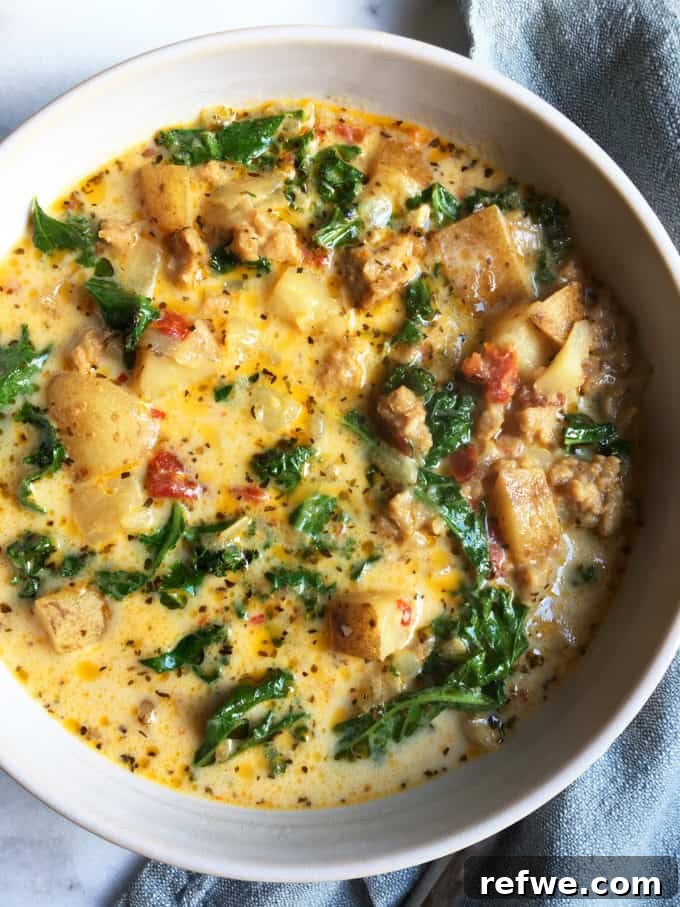 Heartwarming Plant-Based Soups for Cozy Days 6 A hearty bowl of vegetarian Zuppa Toscana with a creamy base, potatoes, kale, and vegetarian sausage.