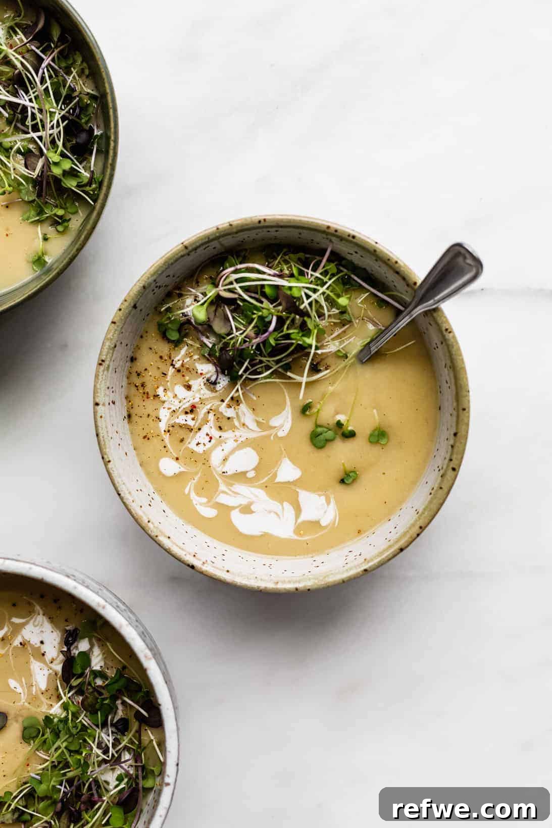 Heartwarming Plant-Based Soups for Cozy Days 7 A creamy, pale roasted garlic soup in a bowl, garnished with fresh herbs.