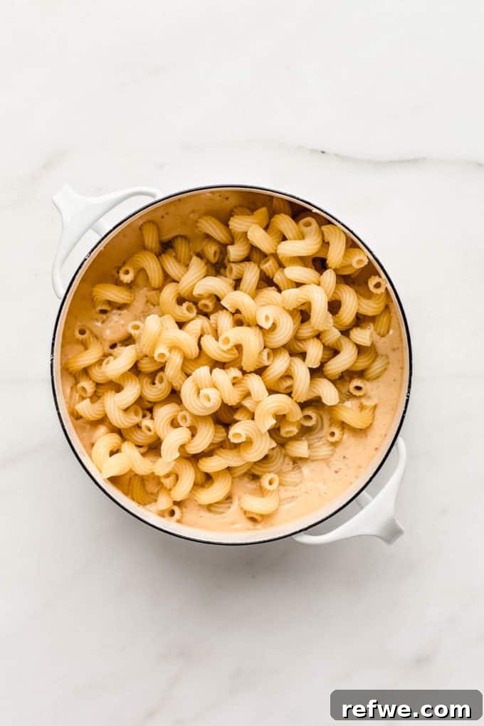 Korean Fusion Vegan Mac and Cheese 4 Close-up shot of vegan kimchi mac and cheese being stirred in a pot, showing the creamy texture and kimchi pieces
