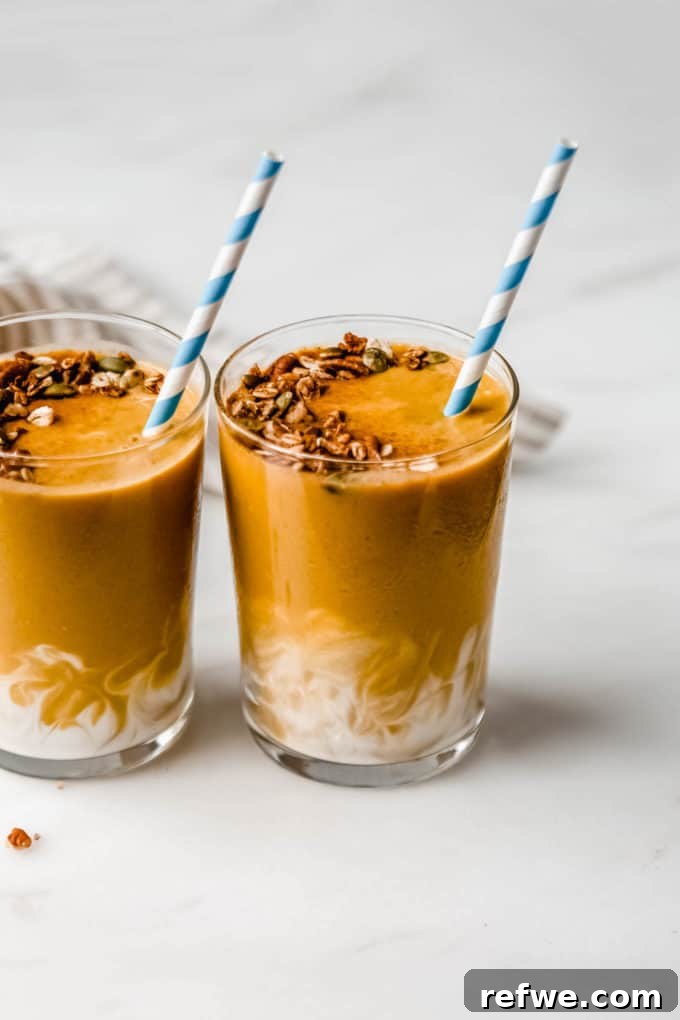 Golden Pumpkin Spice Blend 3 Two enticing pumpkin smoothies stand side-by-side, each adorned with a playful striped blue straw, inviting a refreshing sip.