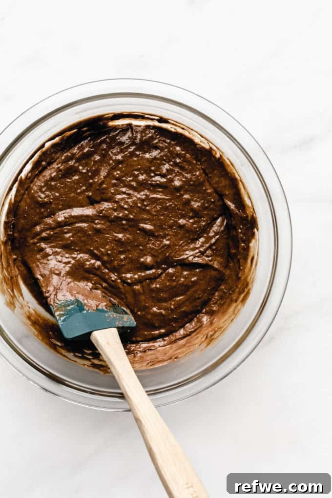 Wholesome Chocolate Pumpkin Delight 5 A mixing bowl filled with rich, dark chocolate pumpkin bread batter, gently folded with a spatula, showing its moist and consistent texture.