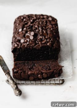A loaf of healthy chocolate pumpkin bread topped with chocolate chips with a small knife on the side