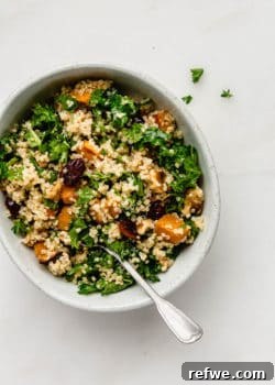 Quinoa and kale salad with sweet potatoes and cranberries in a bowl with a spoon