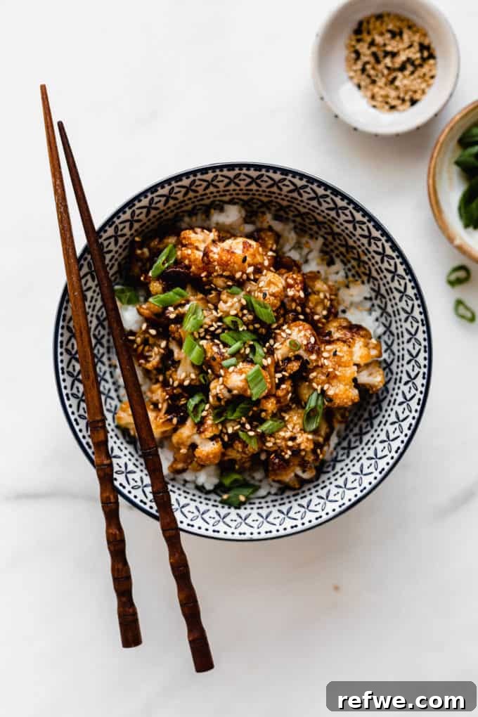 Spicy Peanut Kung Pao Cauliflower 6 Delicious Kung Pao cauliflower in a blue serving bowl, adorned with green onions and wooden chopsticks beside it.