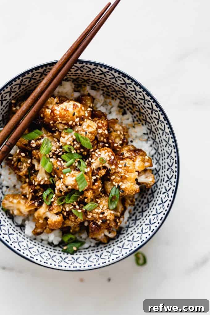 Spicy Peanut Kung Pao Cauliflower 7 A close-up of Kung Pao cauliflower topped with vibrant green onions and sesame seeds, showcasing the rich sauce.