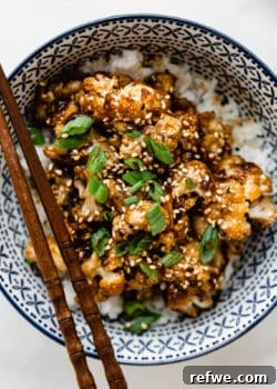 Roasted cauliflower with sauce topped with green onions in a blue bowl