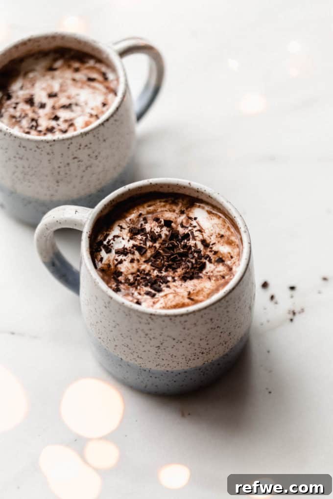 Velvet Vegan Hot Chocolate 6 Two white speckled cups with vegan hot chocolate in them topped with chocolate shavings, ready to be enjoyed