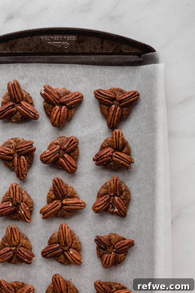 Wholesome Chocolate Turtles 6 A baking sheet with date and pecan patties, showcasing 3 pecans placed on each one