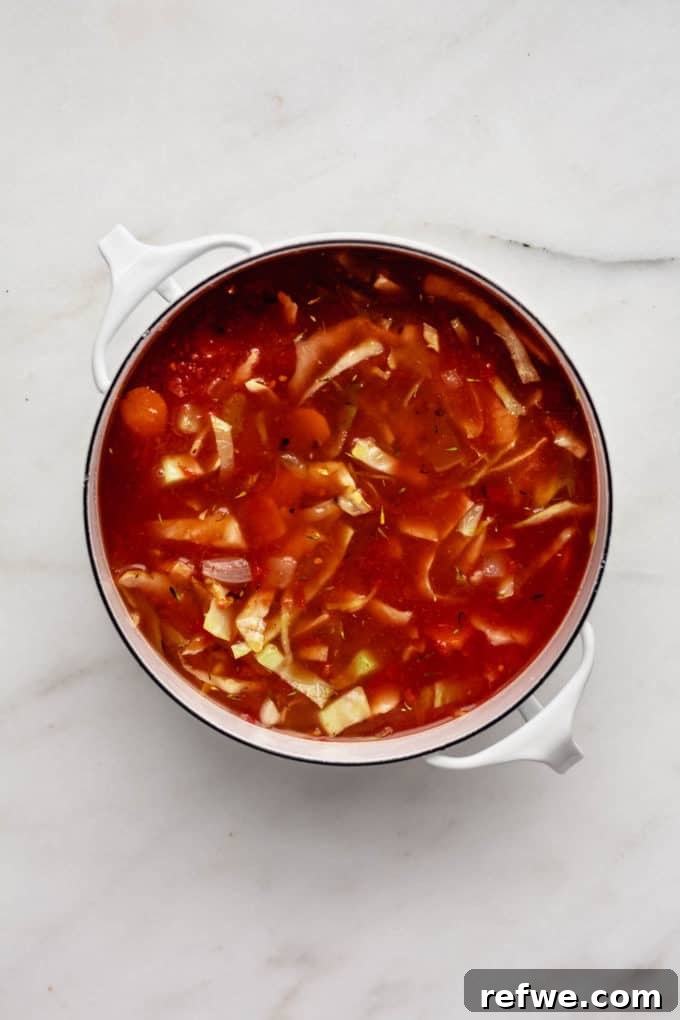 Hearty Vegetarian Cabbage Soup 5 A large white pot of bubbling cabbage soup sits invitingly on a marble board, signaling warmth and comfort