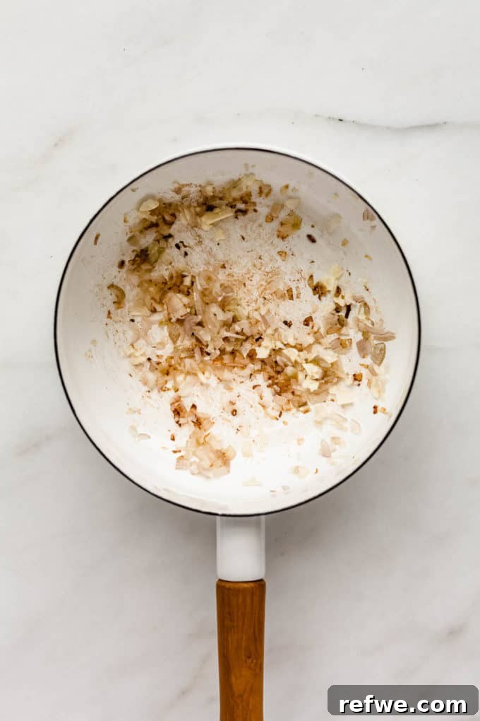 Golden Turmeric Rice 3 A white pot with sautéed shallots and garlic in it, forming the aromatic base for the rice