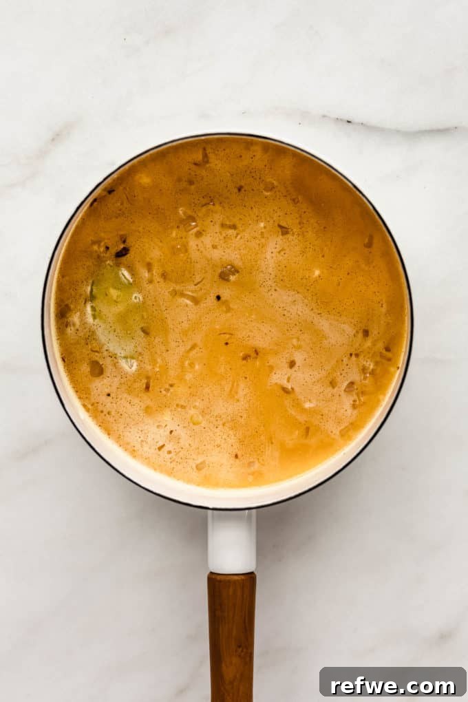 Golden Turmeric Rice 5 A white pot with rice, vegetable stock, and turmeric simmering, covered by a lid