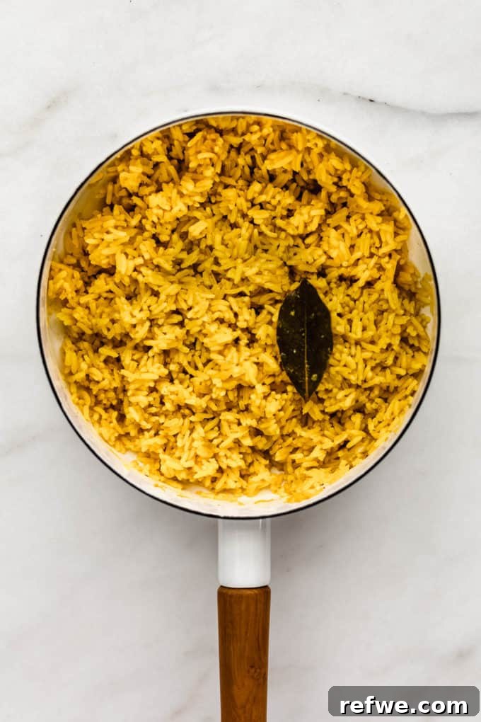 Golden Turmeric Rice 6 A white pot filled with perfectly cooked turmeric rice and a bay leaf, ready to be fluffed