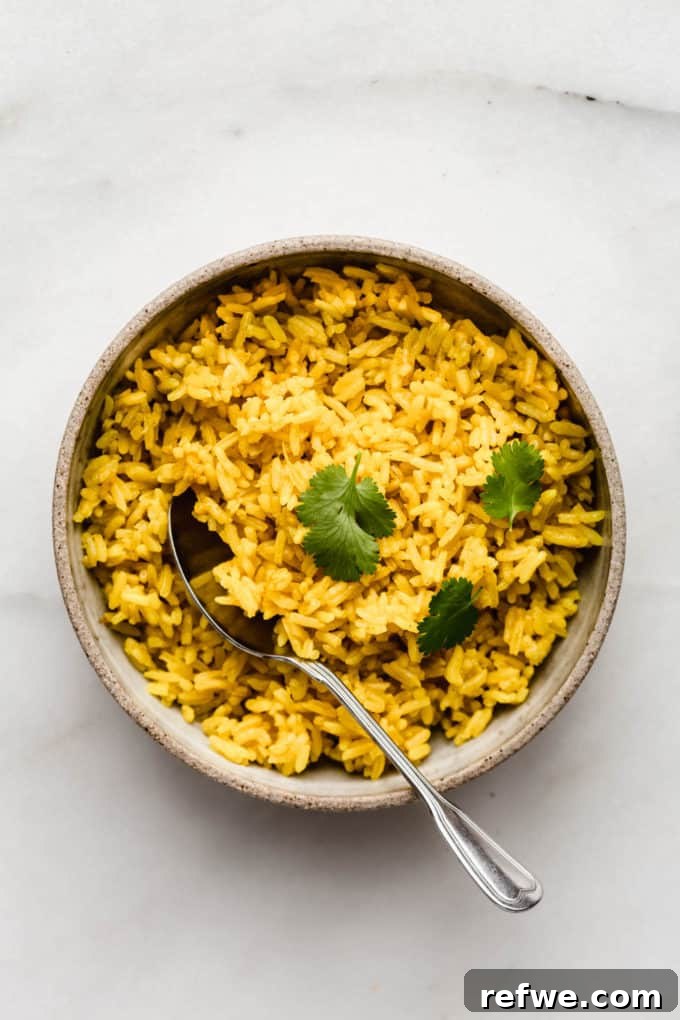 Golden Turmeric Rice 8 A bowl of fluffy turmeric rice with a serving spoon, ready to be enjoyed
