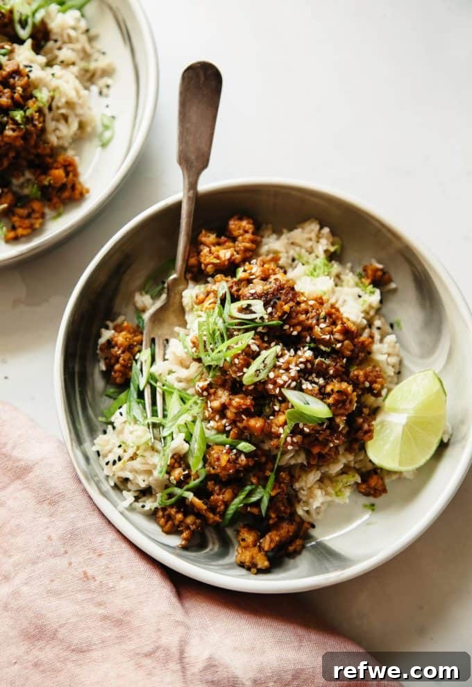 Unlock Tempeh's Potential 23 Recipes and a Full Cooking Guide 11 A stylish white and grey bowl filled with glossy sticky ginger tempeh served alongside aromatic coconut rice, garnished beautifully.