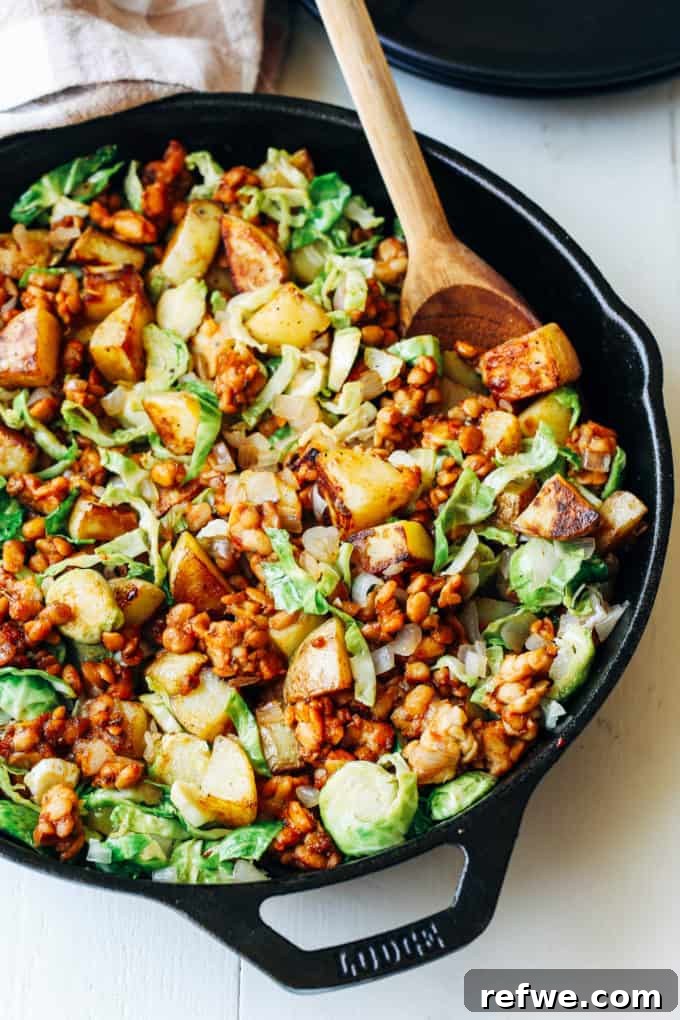 Unlock Tempeh's Potential 23 Recipes and a Full Cooking Guide 14 A cast iron skillet filled with a rustic Smoky Maple Tempeh Hash, featuring crumbled tempeh, crispy potatoes, and roasted Brussels sprouts.