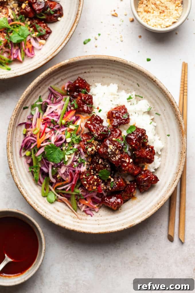 Unlock Tempeh's Potential 23 Recipes and a Full Cooking Guide 15 A vibrant ceramic plate featuring glazed Gochujang Tempeh, served with fluffy rice and a tangy winter slaw, with chopsticks ready.