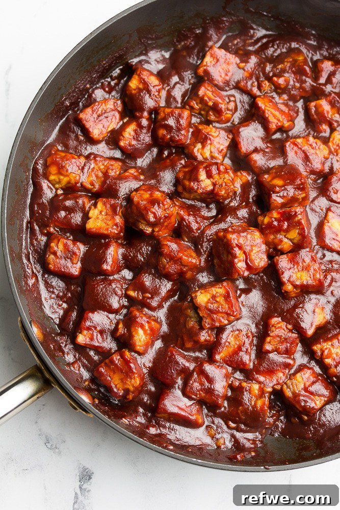 Unlock Tempeh's Potential 23 Recipes and a Full Cooking Guide 20 A skillet filled with succulent, saucy BBQ tempeh cubes, cooked to perfection and ready to serve.