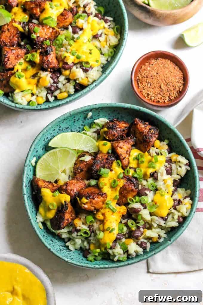 Unlock Tempeh's Potential 23 Recipes and a Full Cooking Guide 10 A vibrant turquoise bowl showcasing Jerk Tempeh with rice, black beans, corn, and a generous drizzle of golden mango-tahini sauce.