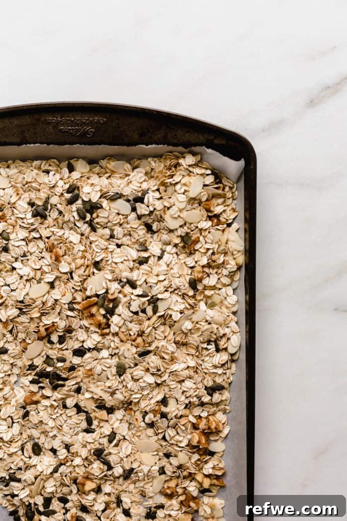 Effortless Wholesome Muesli 4 Muesli ingredients spread on a baking sheet, ready to be toasted in the oven