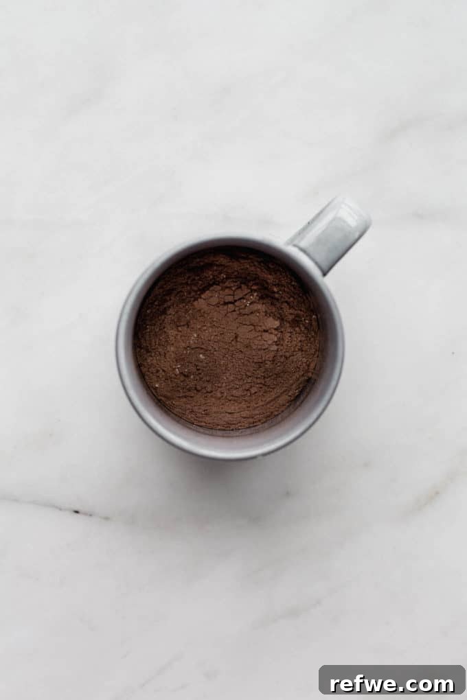 A grey mug with a mix of cocoa powder and flour, representing the initial dry ingredients for the mug cake.