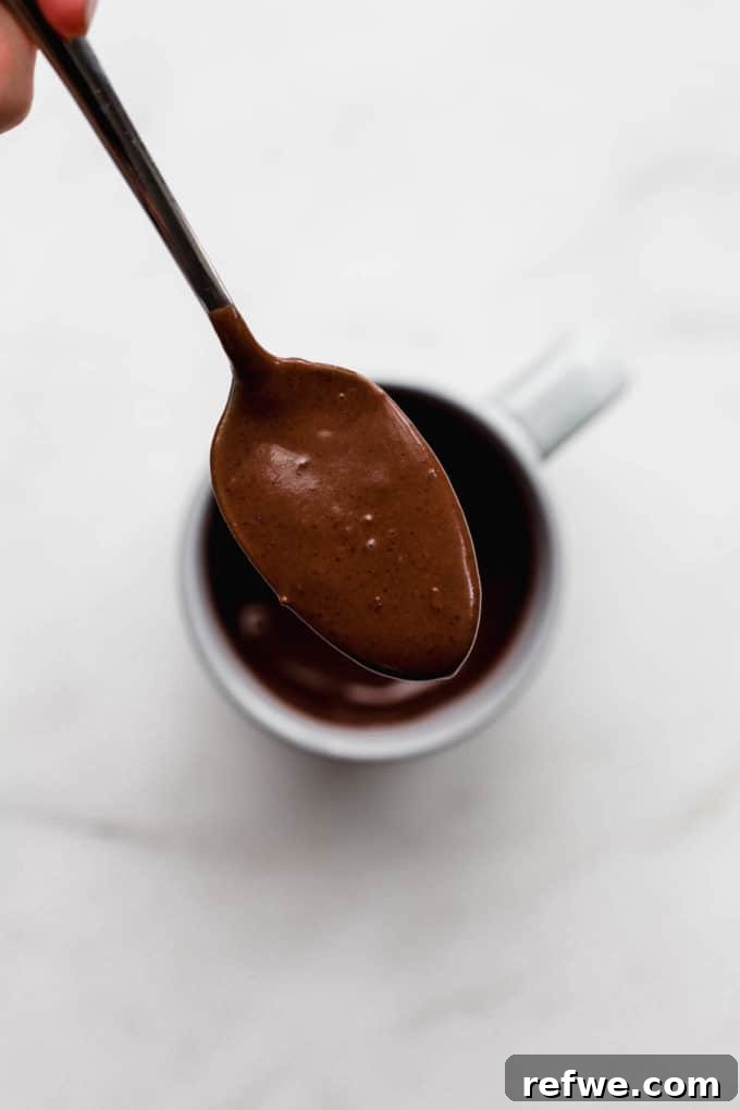 A spoonful of rich, dark chocolate cake batter, showing its smooth consistency.