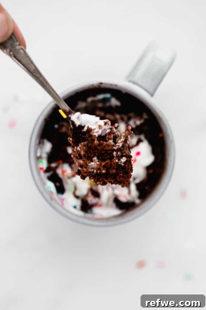 A close-up shot of a spoonful of soft, decadent chocolate mug cake, showcasing its inviting texture.