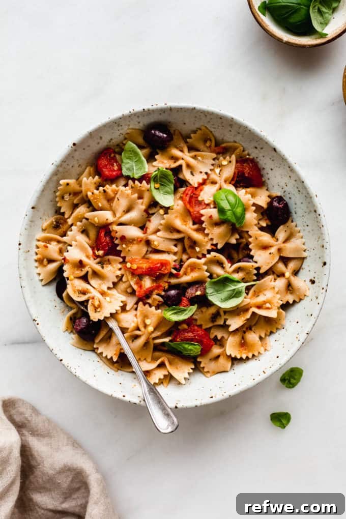 Sun-Drenched Mediterranean Pasta 6 A bowl of Mediterranean pasta topped with fresh basil, with a napkin on the side