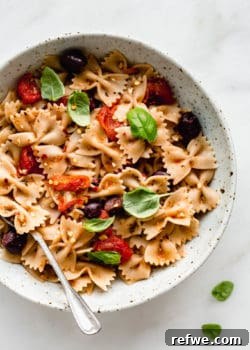 A bowl of farfalle pasta with olives, roasted tomatoes and basil