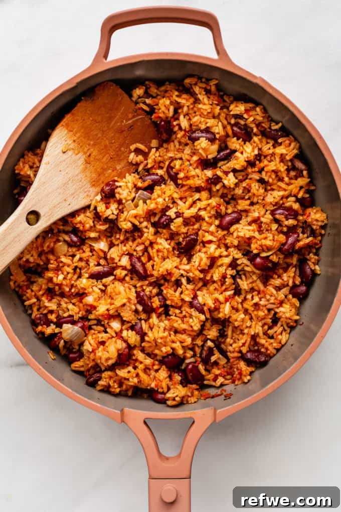 Classic Spanish Red Beans and Rice 6 Spanish rice and beans simmering in a pink pan, covered