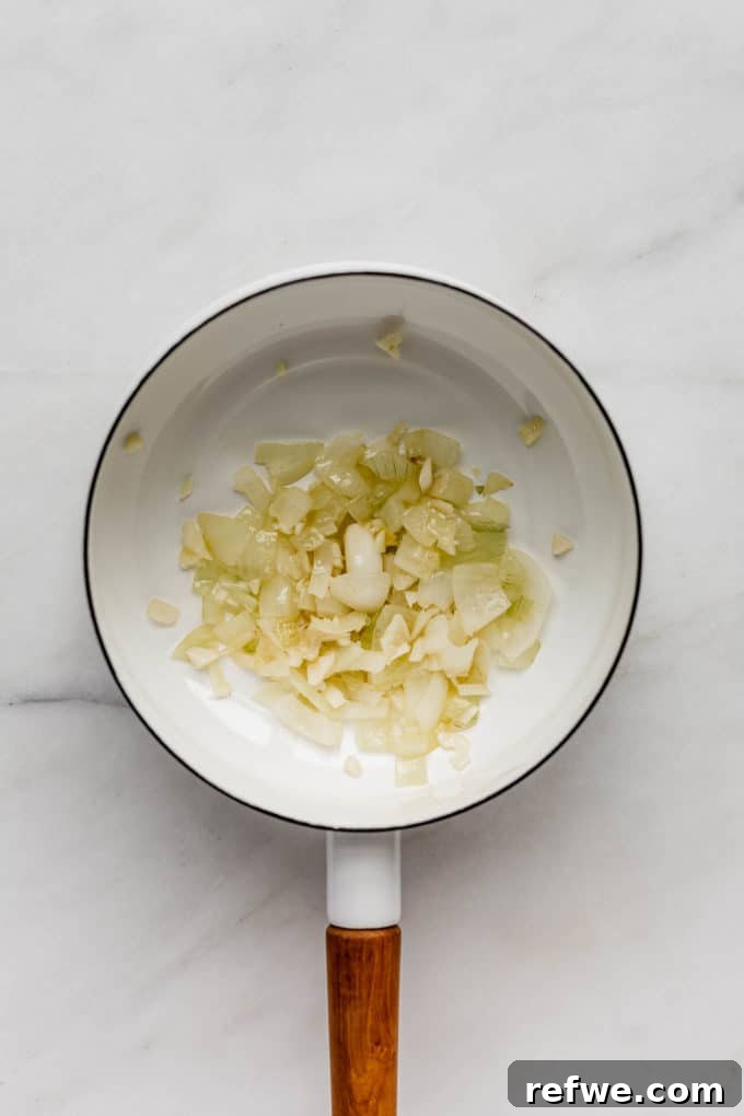 Plant-Powered Mushroom Stroganoff 3 Sautéed onions cooking in a white pot, translucent and fragrant.