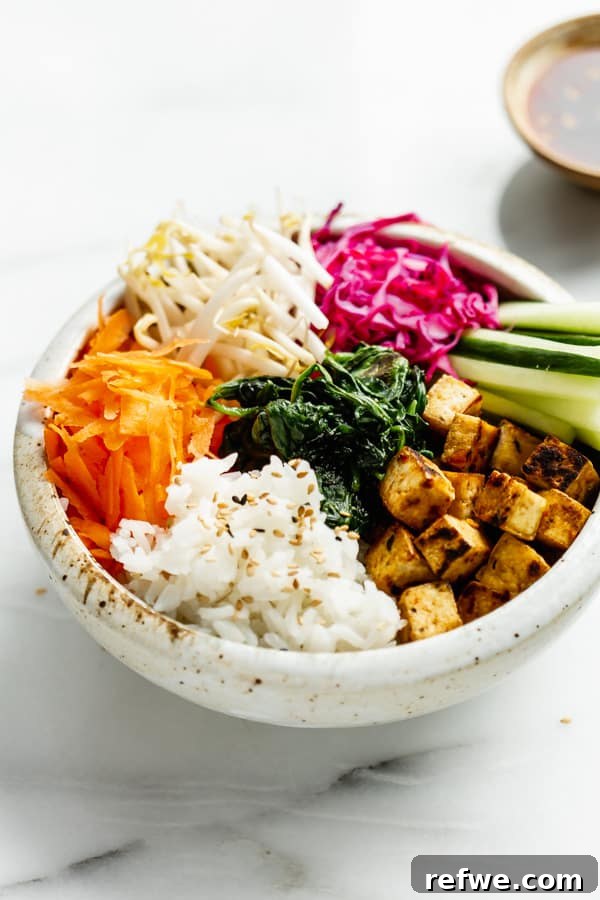 A beautifully presented bowl of Vegan Bibimbap in a white ceramic bowl, showcasing the arranged toppings.